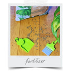 LUCKY TO HAVE® Lucky Sour Pop mini dustpan and broom collecting spilled fertilizer granules on a wooden surface next to houseplants, enabling precise handling of fine materials — save your resources.