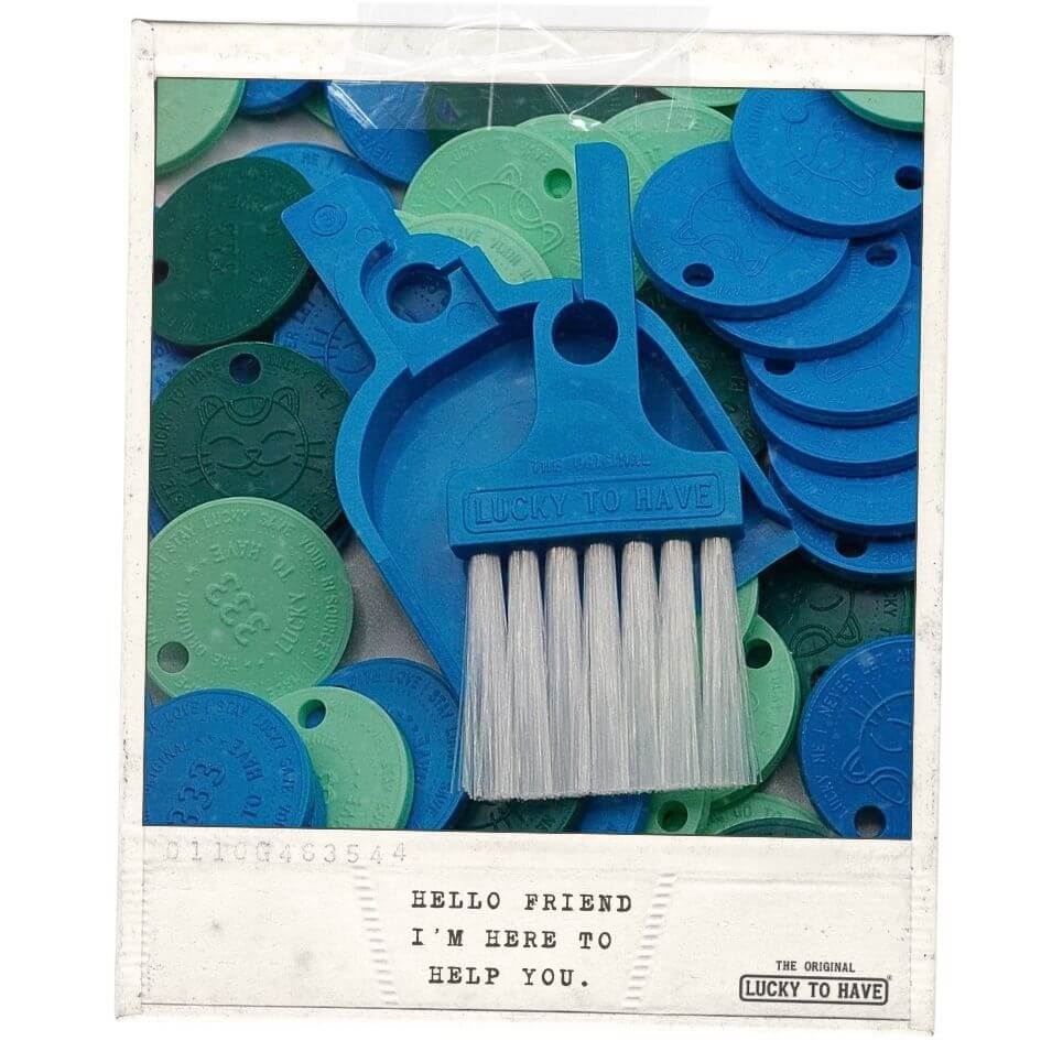 LUCKY TO HAVE® Bora Bora – the smallest broom and dustpan set – lying on colorful Lucky Coins that double as charms, keychains and shopping cart tokens, combining smart sweeping for powders and fine crumbs with playful everyday function.