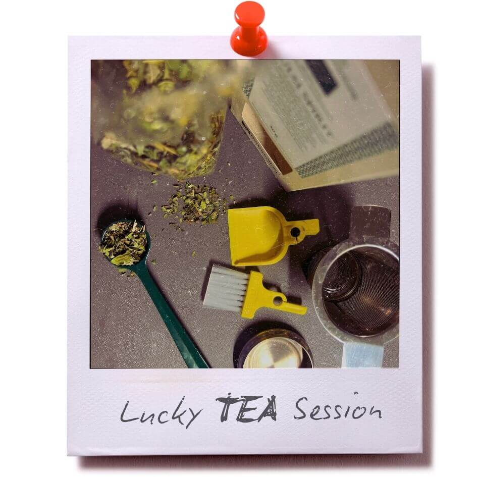LUCKY TO HAVE® Banana yellow smallest broom and dustpan set next to loose tea leaves, showing dried tea herbs scattered on a tabletop with spoon and tea packaging in view. Perfect for tea sessions to clean up spilled leaves.