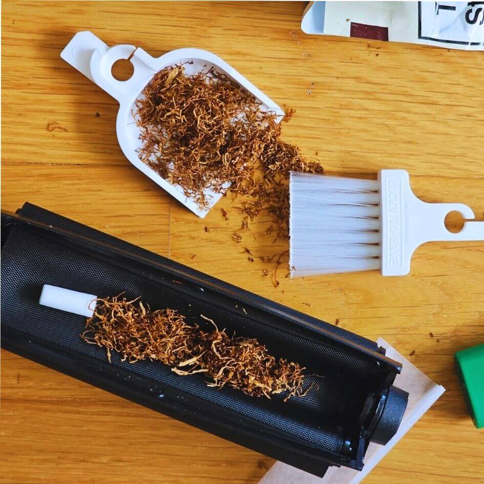 LUCKY TO HAVE® Blanco – the smallest broom and dustpan set – sweeping loose tobacco and fine crumbs next to a cigarette rolling machine, making precise handling of tobacco clean, easy and efficient.