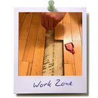 LUCKY TO HAVE® smallest broom and dustpan set used on a wooden floor renovation site, sweeping fine construction dust and debris from a narrow gap between floorboards.