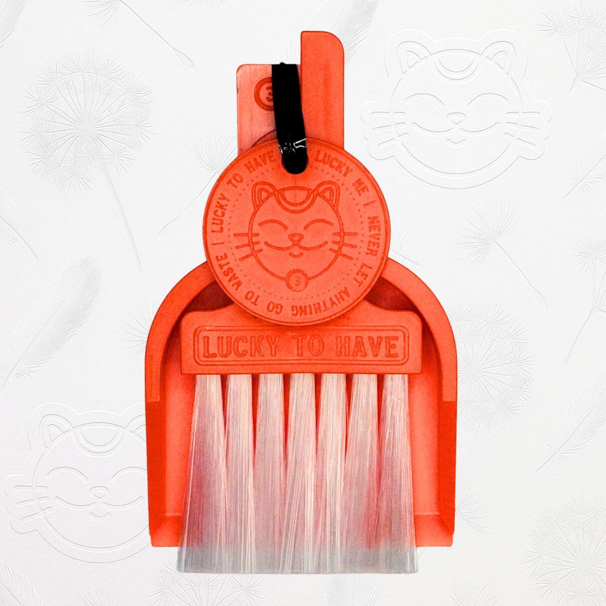 LUCKY TO HAVE® neon orange mini dustpan set presented in front of the signature brand-style wallpaper.