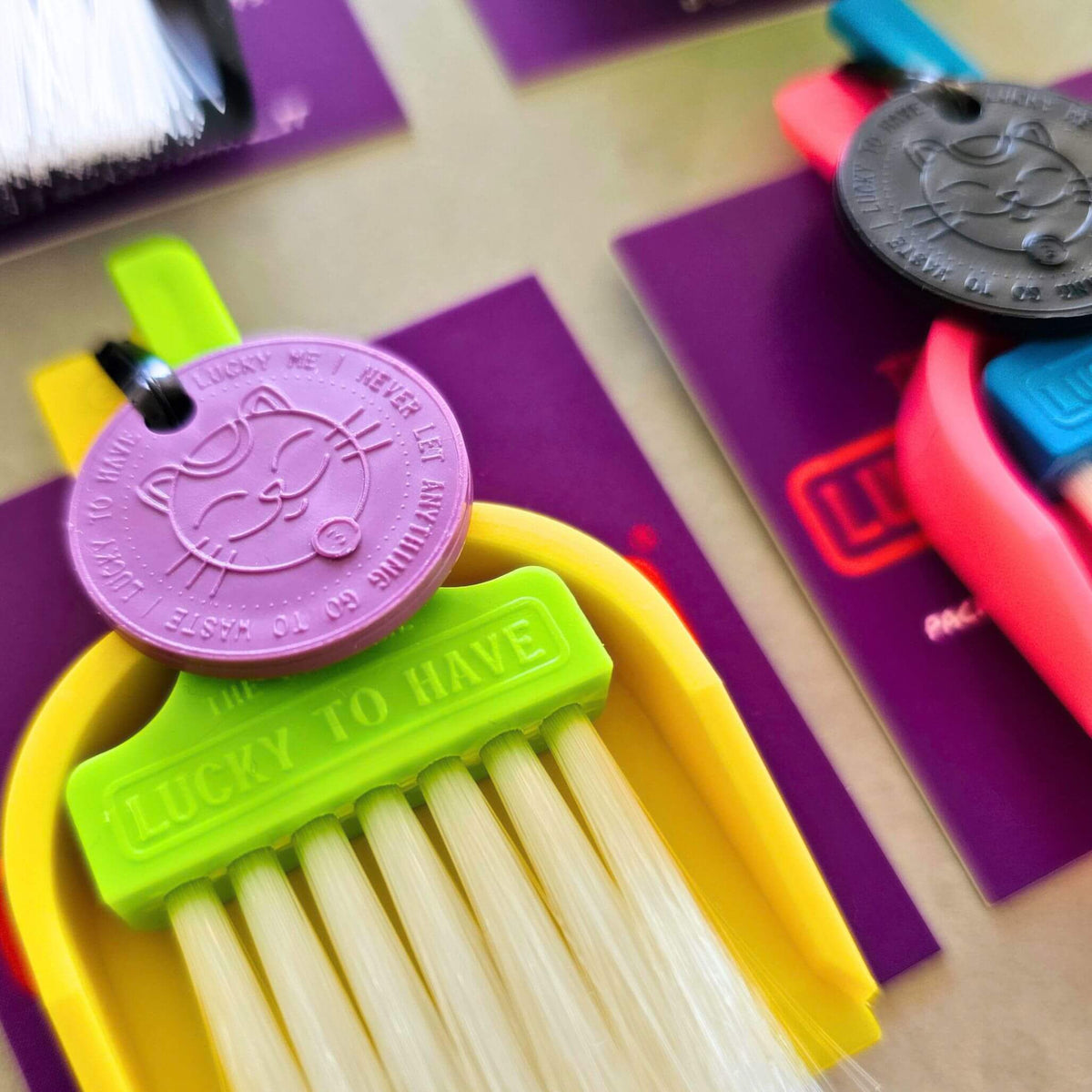 Close-up of a LUCKY TO HAVE® mini broom set with a lime green brush, yellow dustpan and purple Lucky Coin, for sweeping powders and fine crumbs.