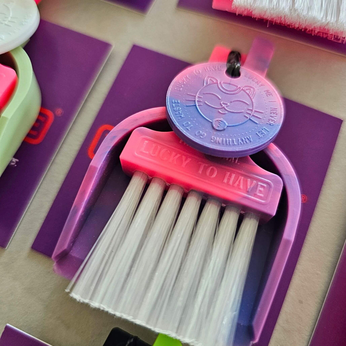 Rainbow Lucky Limited Edition by LUCKY TO HAVE®: mini broom set for powders and fine crumbs, with a pink-purple-blue gradient, white bristles and matching Lucky Coin.