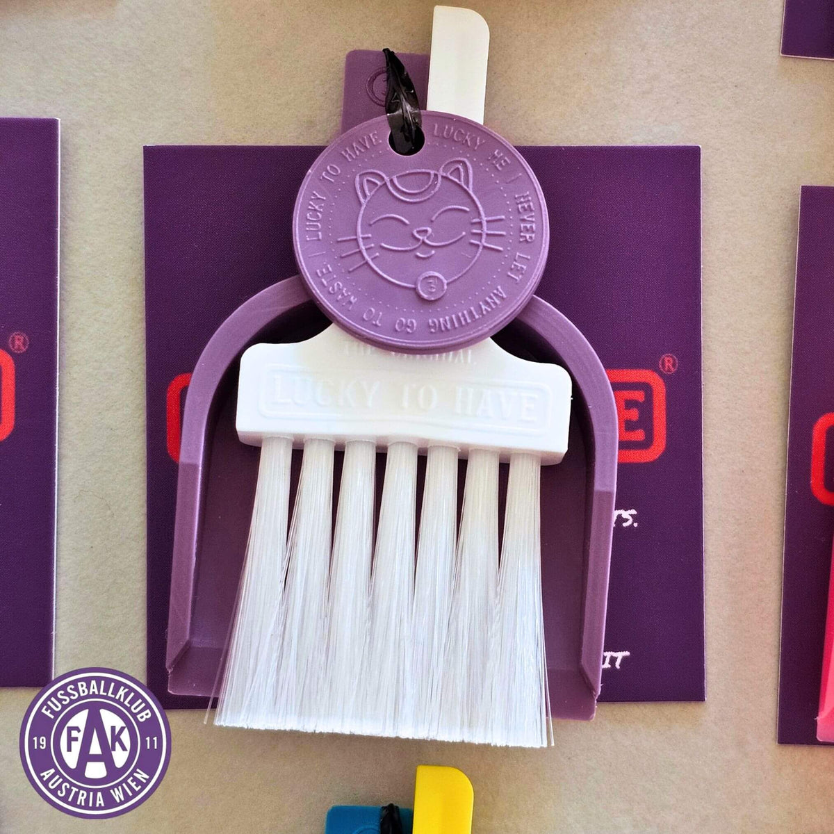 Custom Lucky by LUCKY TO HAVE® with a white broom, purple pan and purple Lucky Coin, inspired by FK Austria Wien’s team colours, with the club logo shown beside it.