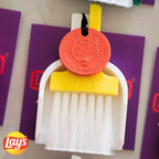 Custom Lucky by LUCKY TO HAVE® with a yellow broom, white pan and orange Lucky Coin, inspired by Lay’s brand colours, with the Lay’s logo shown beside it.