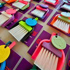 Colourful LUCKY TO HAVE® mini broom sets for powders and fine crumbs, featuring a purple brush in a pink dustpan with a pale green Lucky Coin.