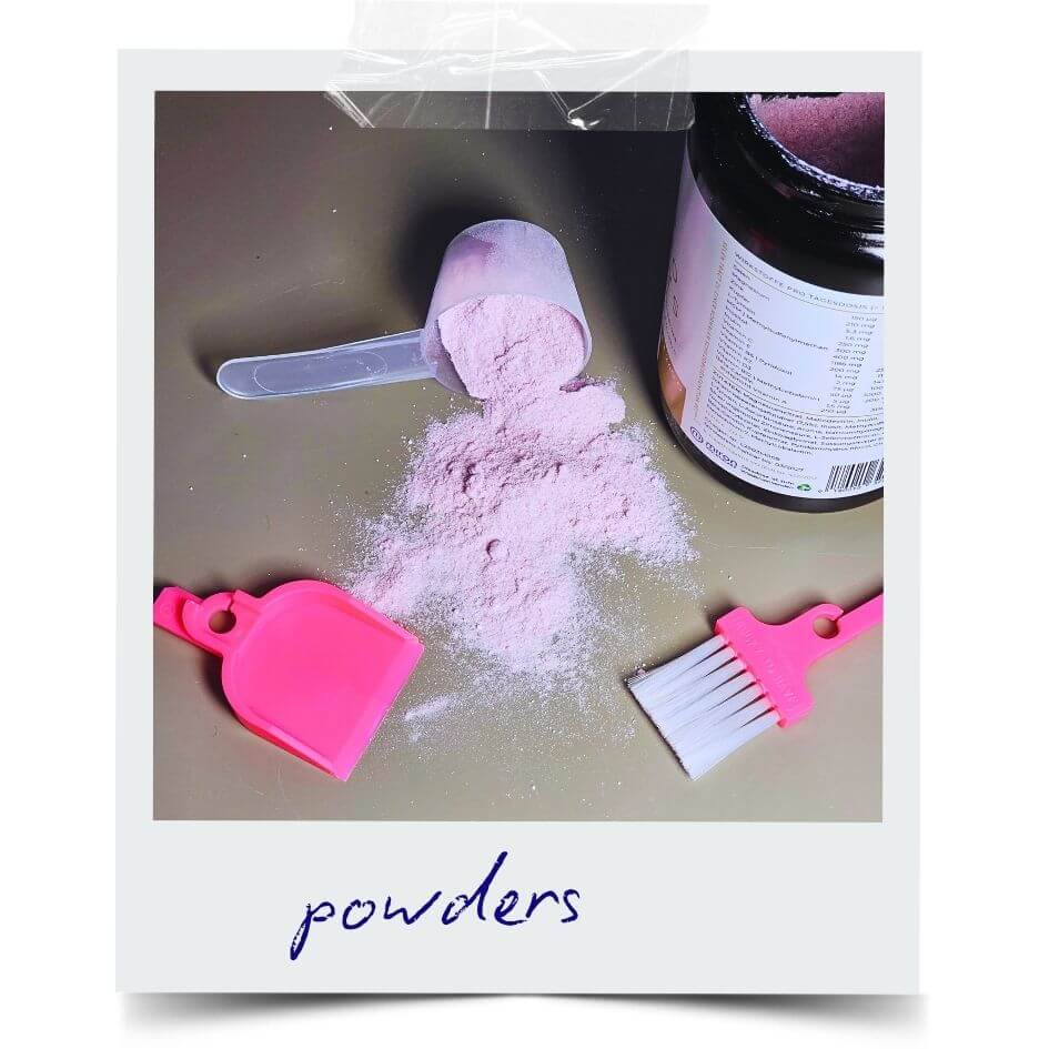 LUCKY TO HAVE® Babe in pink smallest broom and dustpan set next to spilled supplement powder and a measuring scoop, showing fine powder scattered on a tabletop surface.
